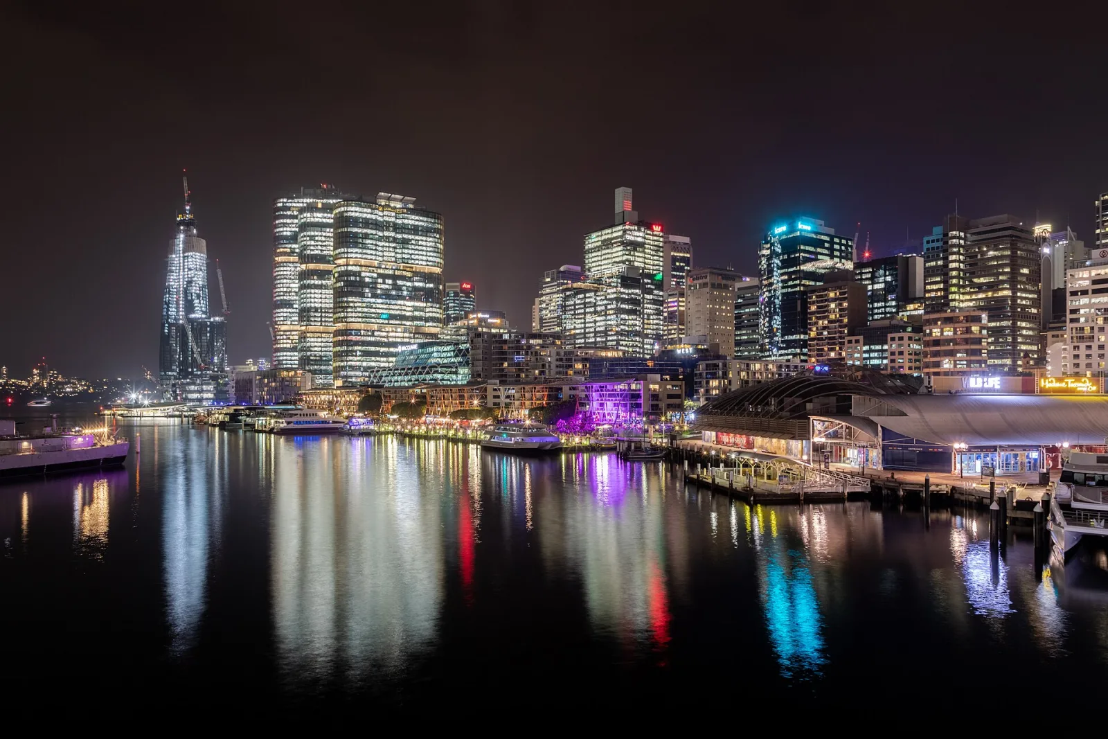 King Street Wharf at Darling Harbour, Sydney, New South Wales, AustraliaDarling Harbour in Sydney is located on the eastern edge of the city center and has a long and varied history. Originally, the area was a natural bay and river connection used by the Gadigal and Eora communities. In the 19th century, the harbour developed into an important hub for goods, shipping, and naval activities, with customs facilities, shipyards, and warehouses dominating the landscape. Through land reclamation and redevelopment, Darling Harbour gradually transformed from a working port to a leisure, recreation, and exhibition district.In the 1980s, a strategic shift took place: urban redevelopment, new infrastructure, and major events led to increased use as an urban leisure and MICE location. With the Bicentennial in 1988, the area was redesigned, and museums, convention centers, restaurants, and green spaces were created. Today, Darling Harbour combines history with science, culture, and leisure and remains a vibrant attraction in the heart of Sydney.